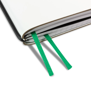 Nahaufnahme eines Notizbuches mit einem grasgrünen Doppelbuchband, das aus den weißen Seiten hervorsteht.