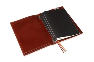 Geöffnetes Leder-Notizbuch von X47 mit mehreren Einlageheften – Wer hat’s erfunden? Der Clou liegt in der Schweizer Präzisionsmechanik der Federschienen.