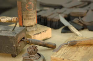 Werkzeuge Traditionelle Handwerkzeuge zur Bearbeitung von Leder, wie Schneidemesser und Kantenformer, die für die Herstellung einer hochwertigen Lederhülle oder anderer Lederwaren in einer Werkstatt verwendet werden.